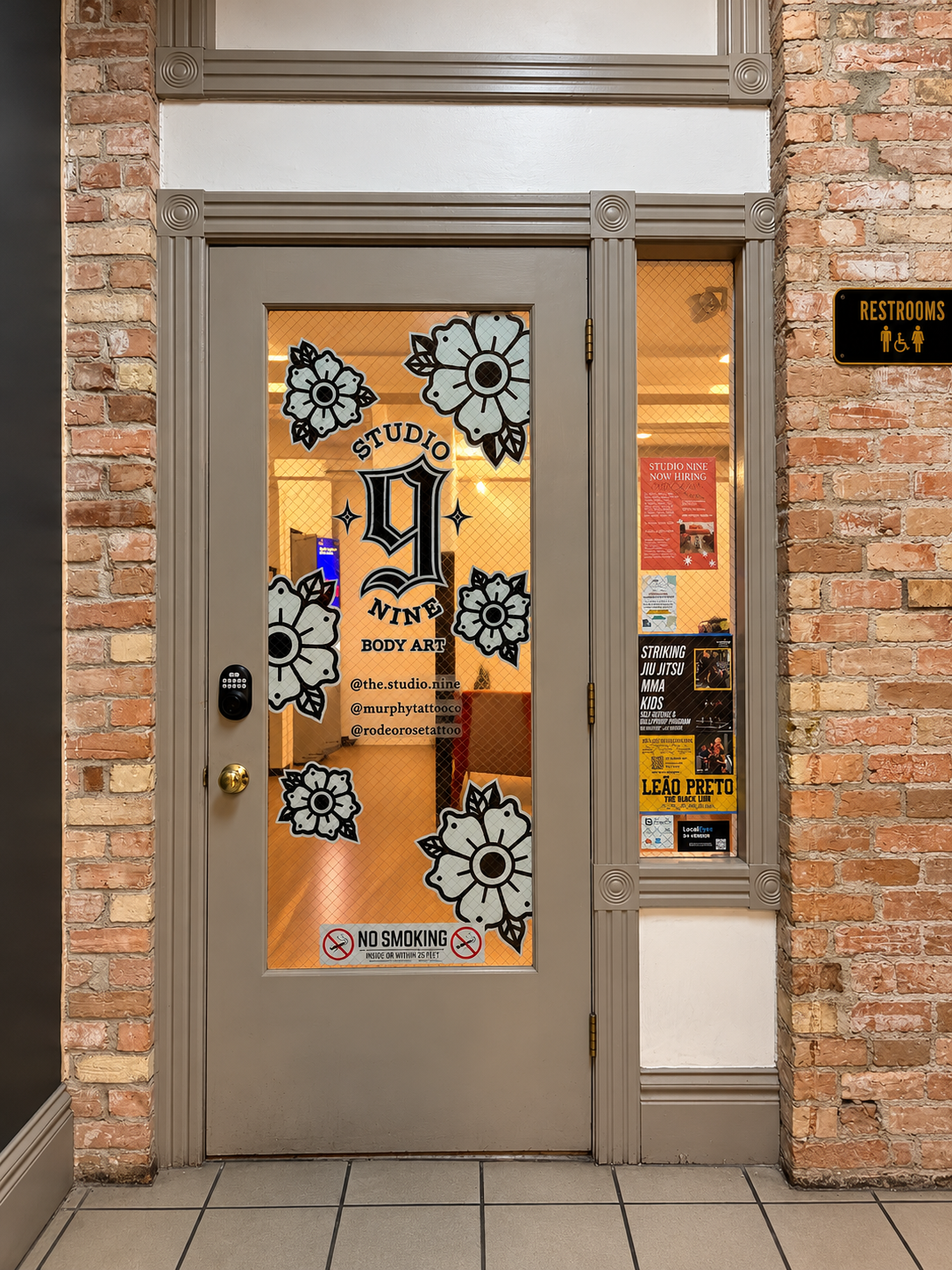 Gray Studio Nine door with black and white floral artwork, beside the restroom sign in the interior hallway